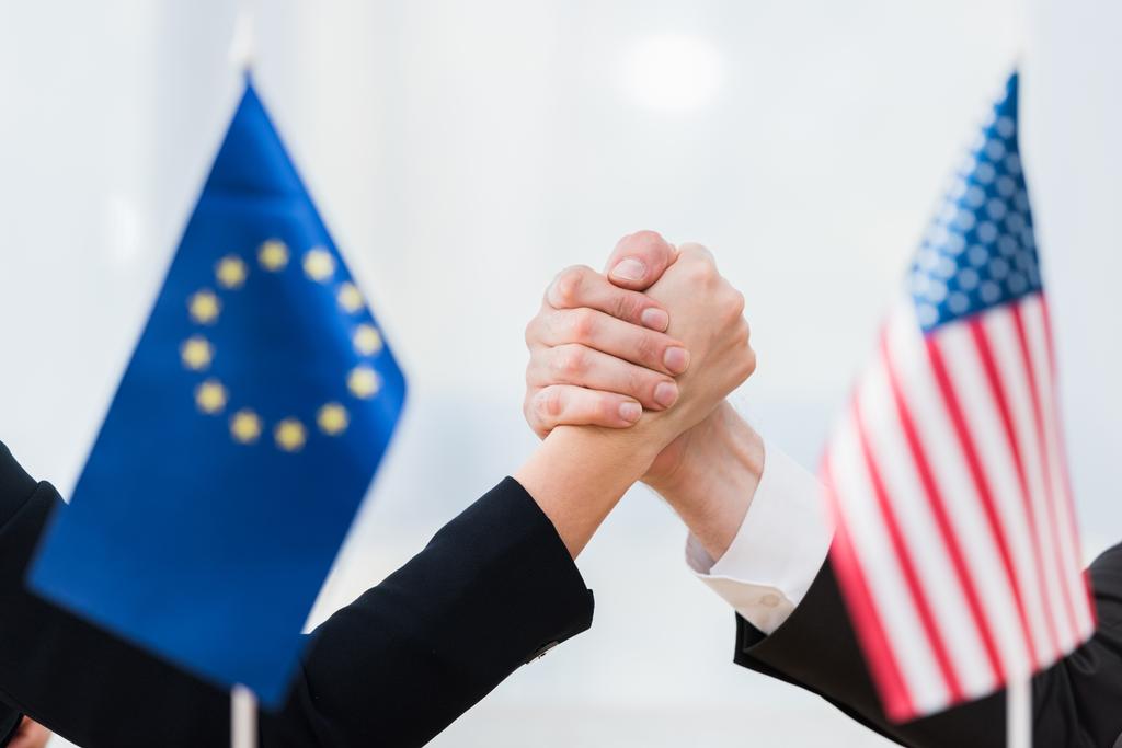 foco seletivo dos diplomatas de mãos dadas perto das bandeiras dos EUA e da união europeia
 - Foto, Imagem