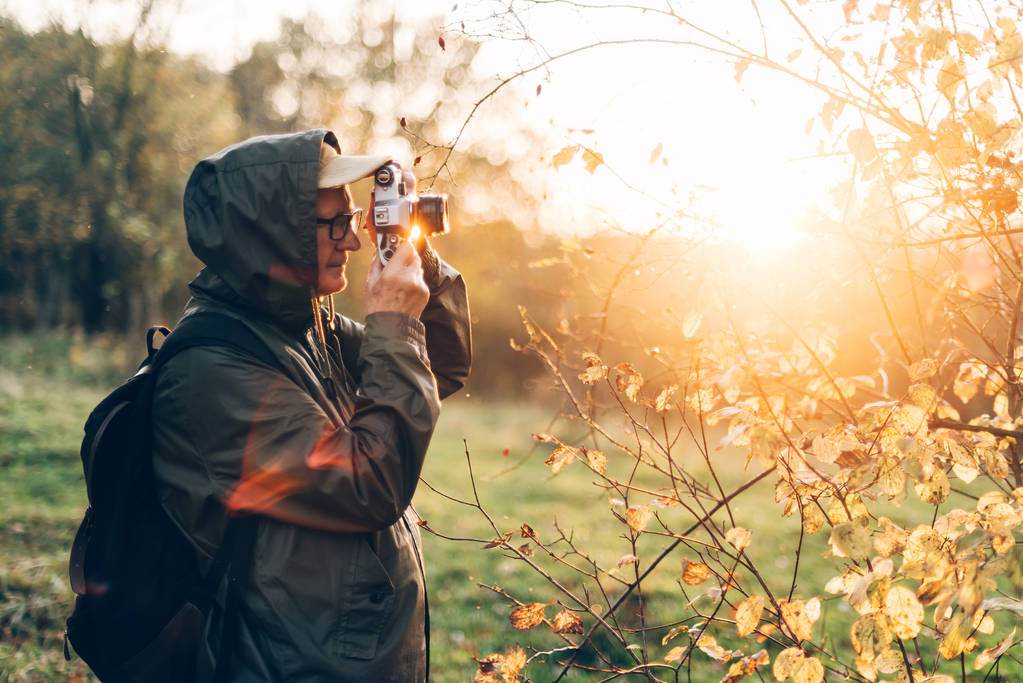 Senior man taking photo in nature. Man photographing autumn forest. - Photo, Image