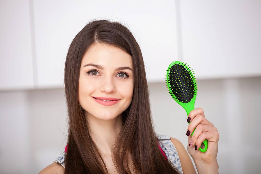 Dívka drží kartáč na vlasy bez vlasů a usmívá - Fotografie, Obrázek