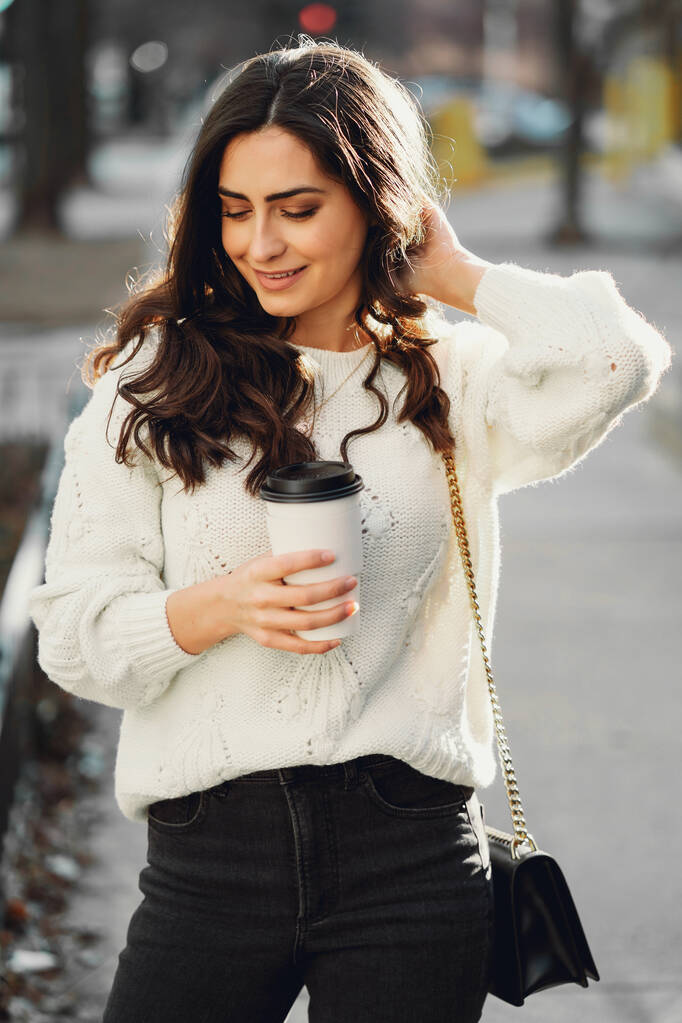 Aranyos barna egy fehér pulóverben egy városban. - Fotó, kép
