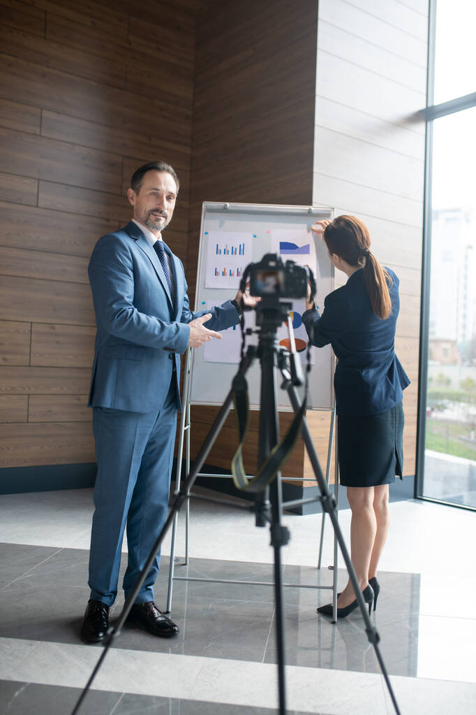 Geschäftsmann steht vor Kamera, während er Blog mit Geschäftsfrau filmt - Foto, Bild