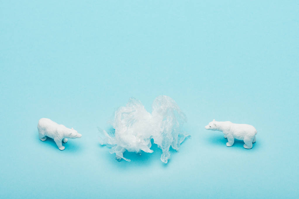 Toy polar bears with polyethylene bag on blue background, environmental pollution concept - Photo, Image
