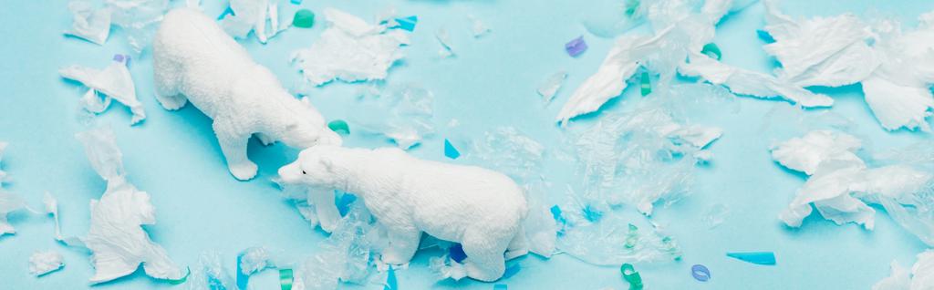 青い背景にポリエチレンとプラスチック片を持つおもちゃのホッキョクグマのパノラマショット、動物福祉の概念 - 写真・画像