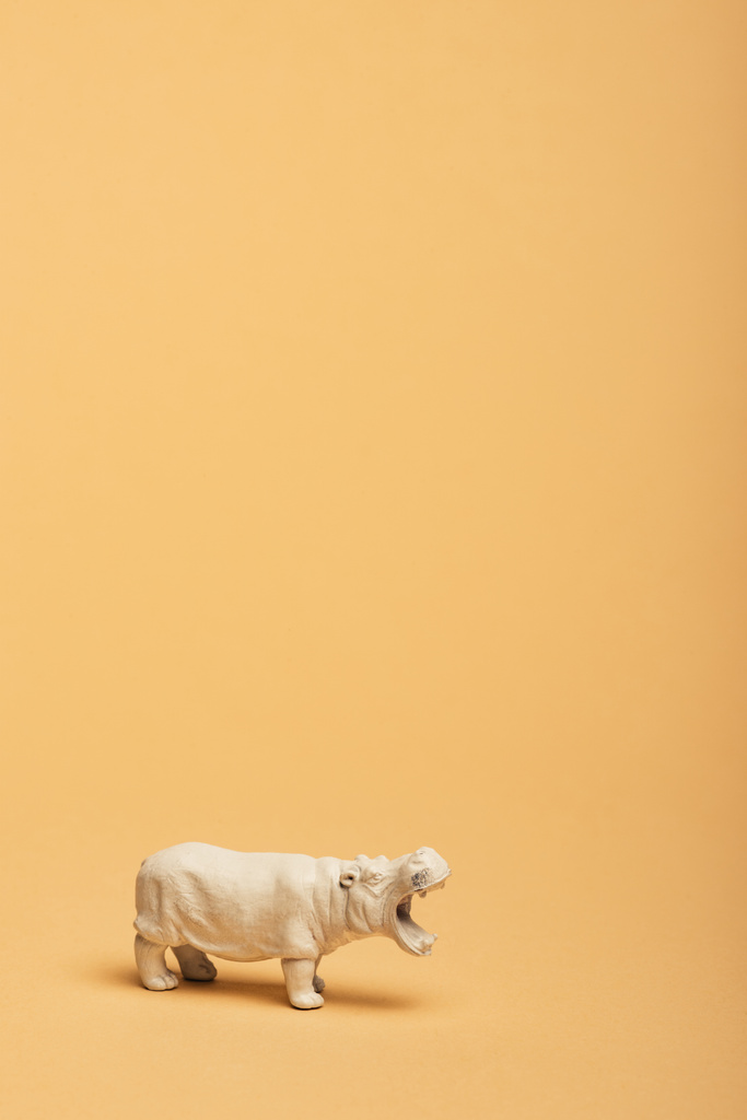 Sarı arka planda beyaz oyuncak hipopotam, hayvan refahı konsepti - Fotoğraf, Görsel