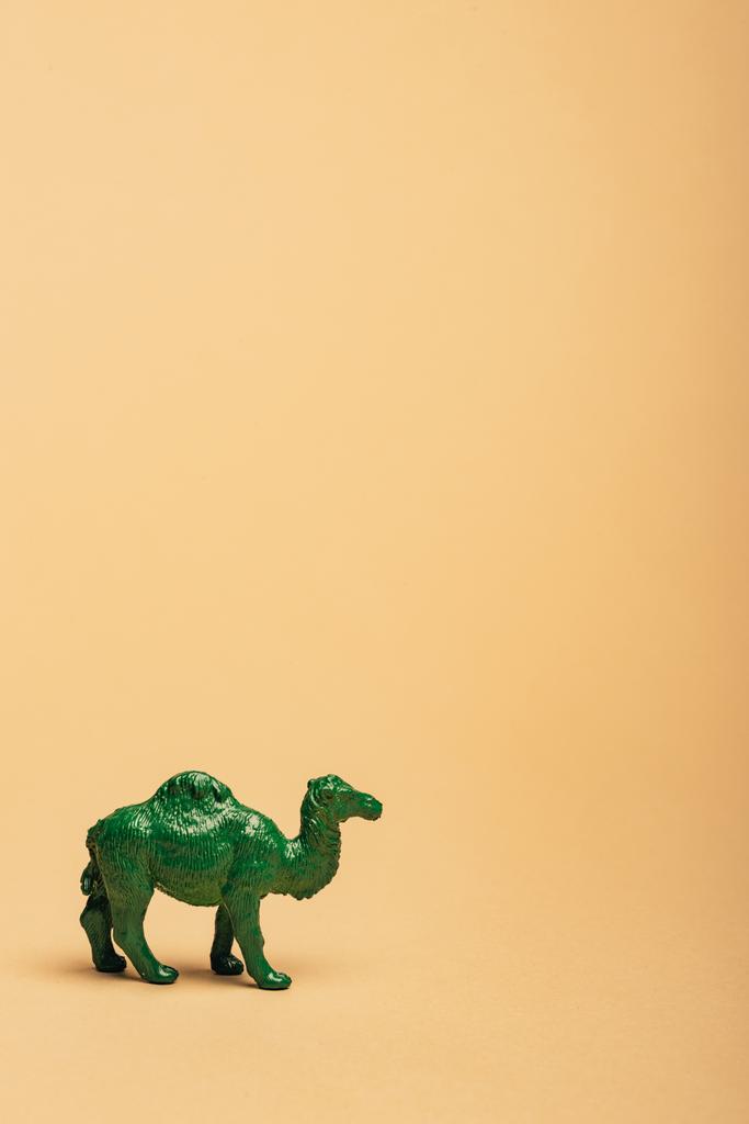 Green toy camel on yellow background, animal welfare concept - Photo, Image