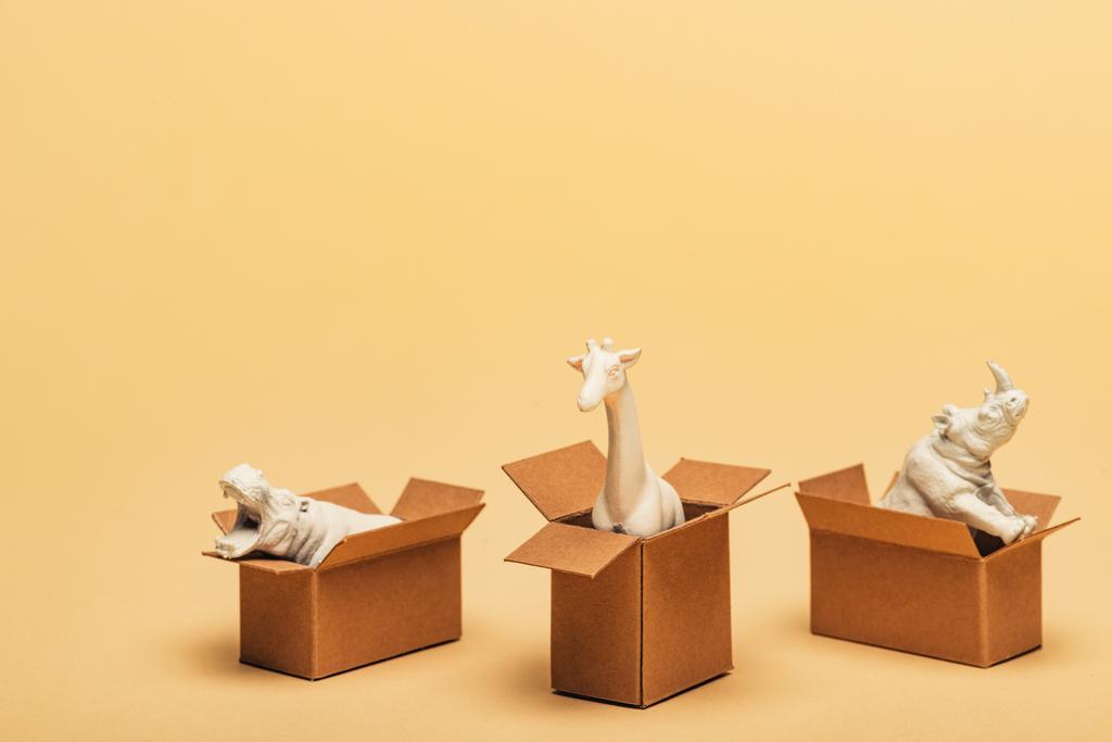 Белый бегемот, носорог и жираф в картонных коробках на желтом фоне, концепция благополучия животных
 - Фото, изображение