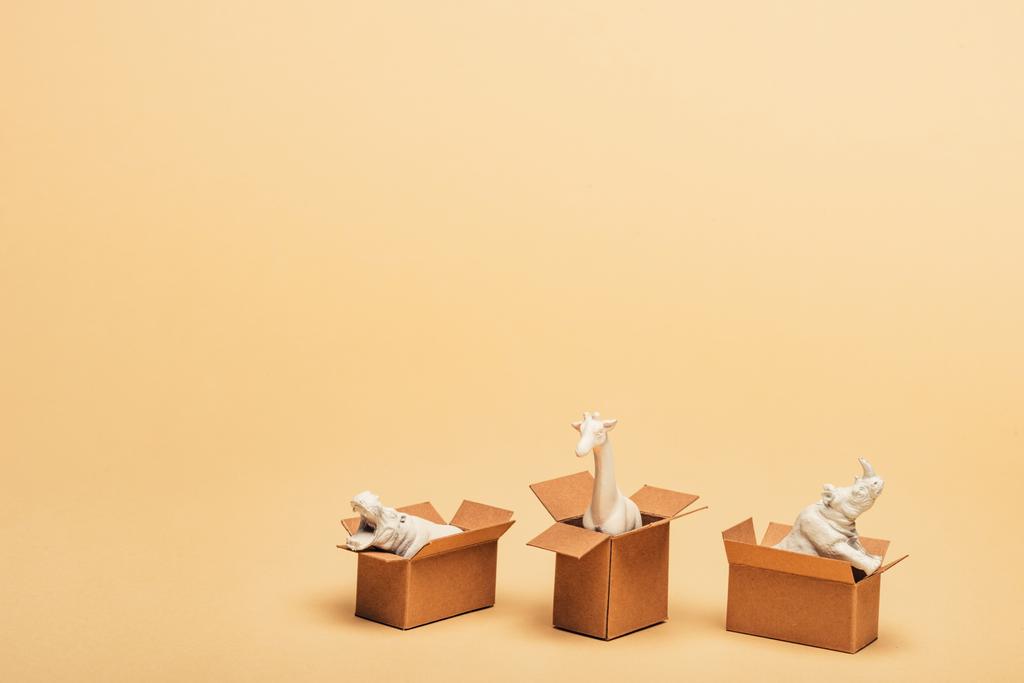 ippopotamo giocattolo bianco, rinoceronte e giraffa in scatole di cartone su sfondo giallo, concetto di benessere animale
 - Foto, immagini
