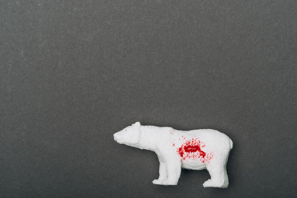 Top view of white toy bear with blood on grey background, killing animals concept - Photo, Image