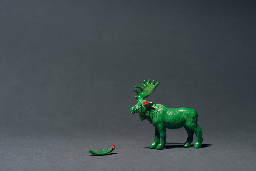 Green toy moose with horn on grey background, hunting for horns concept - Photo, Image