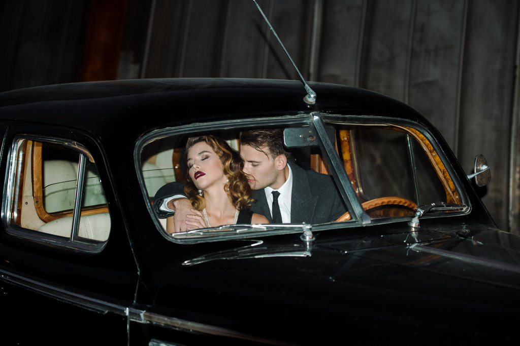 handsome gangster sitting in retro car with woman  - Photo, Image
