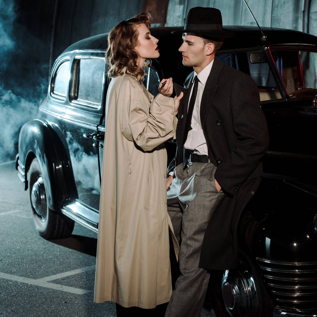 atrakcyjna kobieta stoi w pobliżu przystojny gangster i samochód retro  - Zdjęcie, obraz