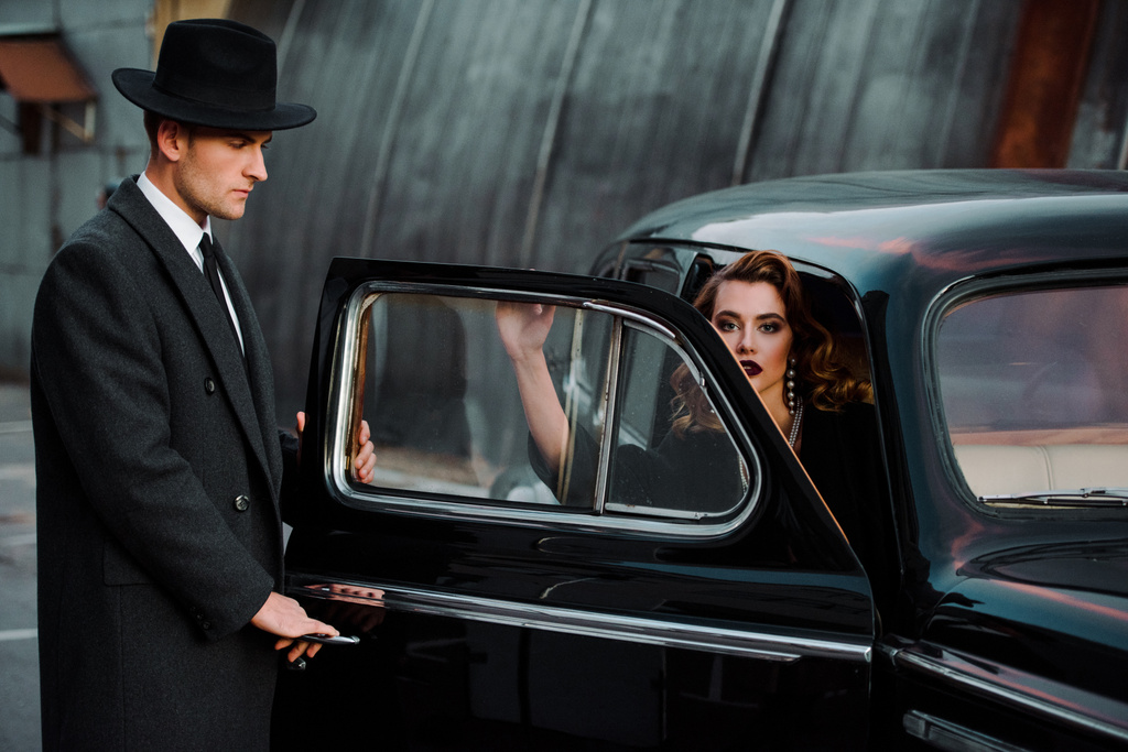 Yakışıklı adam güzel bir kadının yanında arabanın kapısına dokunuyor.  - Fotoğraf, Görsel