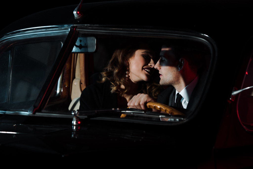 wesoła kobieta patrząc na przystojnego mężczyznę w samochodzie retro  - Zdjęcie, obraz