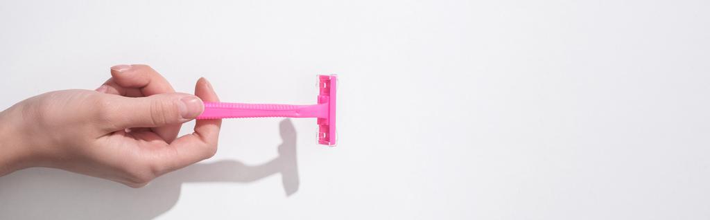 vista cortada da mulher segurando navalha rosa fêmea no fundo branco, tiro panorâmico
 - Foto, Imagem