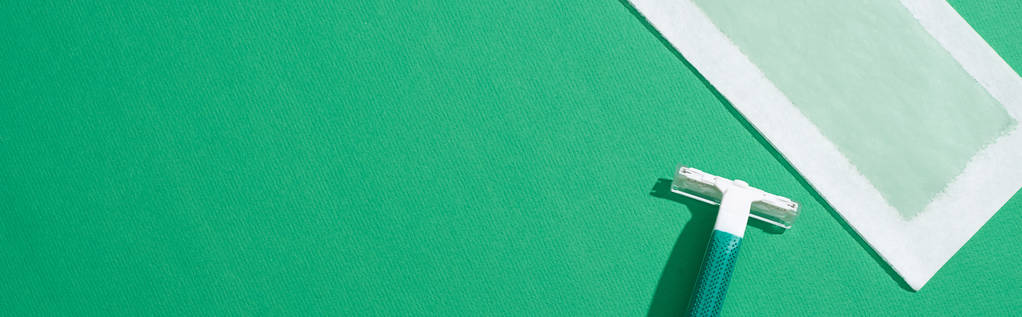 ylhäältä näkymä vihreä kertakäyttöinen partaveitsi ja depilation vaha raita vihreällä pohjalla, panoraama laukaus
 - Valokuva, kuva