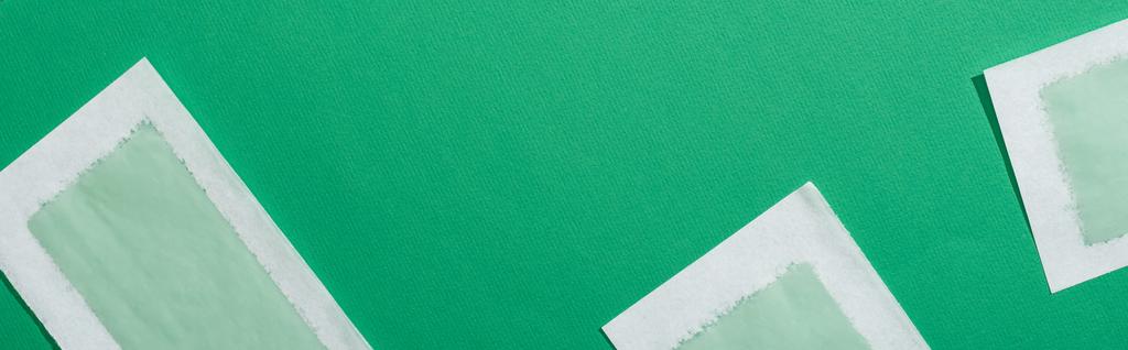 vrchní pohled na zelené depilační voskové pruhy na zeleném pozadí, panoramatický záběr - Fotografie, Obrázek