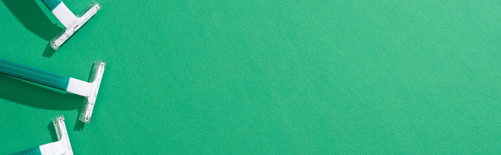 bovenaanzicht van groene wegwerp scheermesjes op groene achtergrond, panoramisch schot - Foto, afbeelding