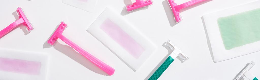 vista superior de afeitadoras verdes y rosadas y rayas de cera depilación sobre fondo blanco, plano panorámico
 - Foto, Imagen