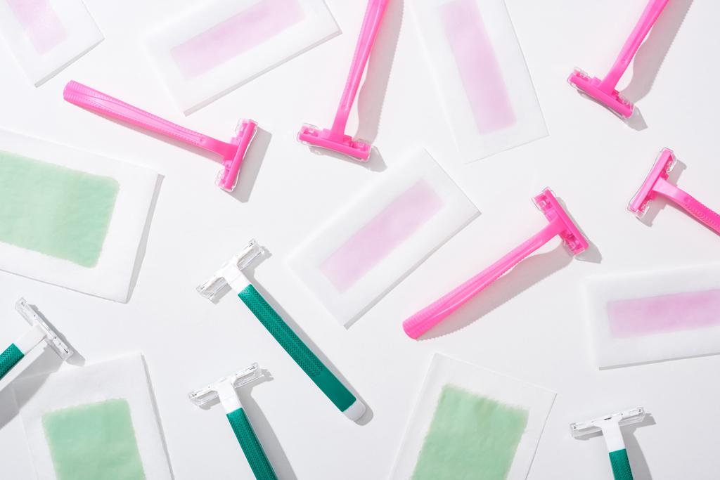vista superior de afeitadoras verdes y rosadas y rayas de cera depilación sobre fondo blanco
 - Foto, Imagen