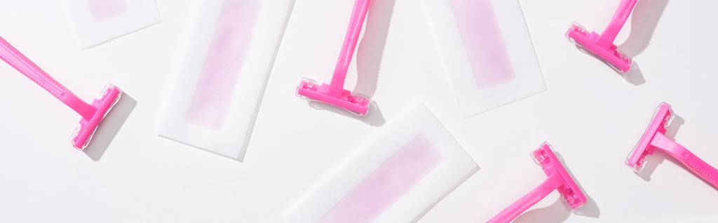 Draufsicht auf rosa Rasierer und Enthaarungswachsstreifen auf weißem Hintergrund, Panoramaaufnahme - Foto, Bild