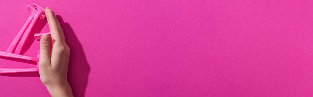 vue recadrée de la main près de rasoirs jetables sur fond rose, vue panoramique
 - Photo, image