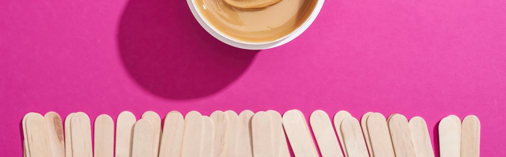 top view of depilation wax in container with sticks on pink background, panoramic shot - Photo, Image