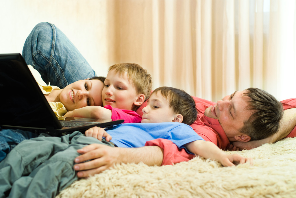 Família deitada no tapete com um laptop
 - Foto, Imagem