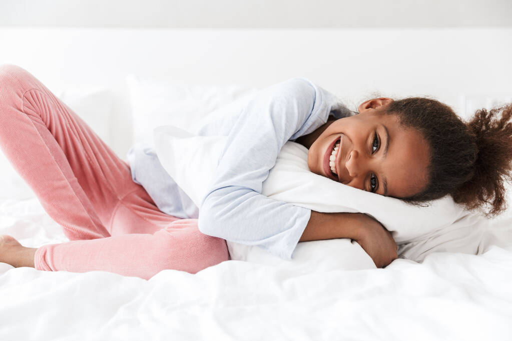Image d'une petite fille afro-américaine souriante et couchée dans son lit
 - Photo, image