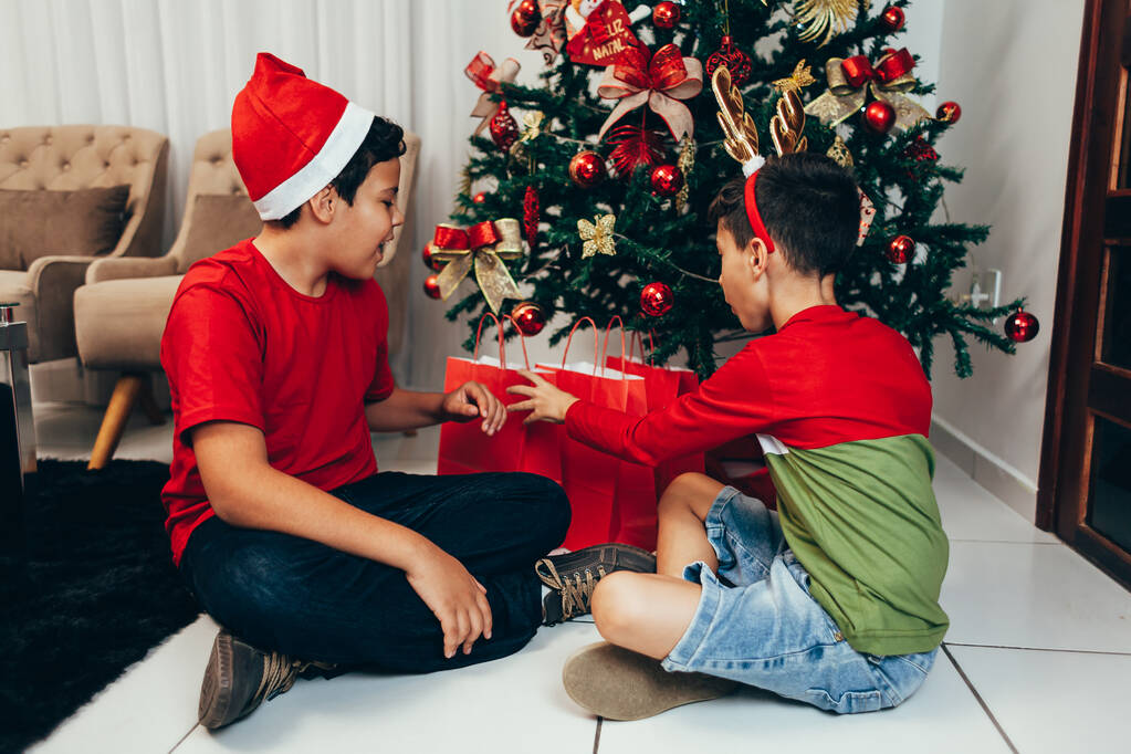 Χαρούμενα και αστεία αγόρια με δώρα και χαρούμενο χριστουγεννιάτικο δέντρο. Καλά Χριστούγεννα και Πρωτοχρονιά έννοια. - Φωτογραφία, εικόνα