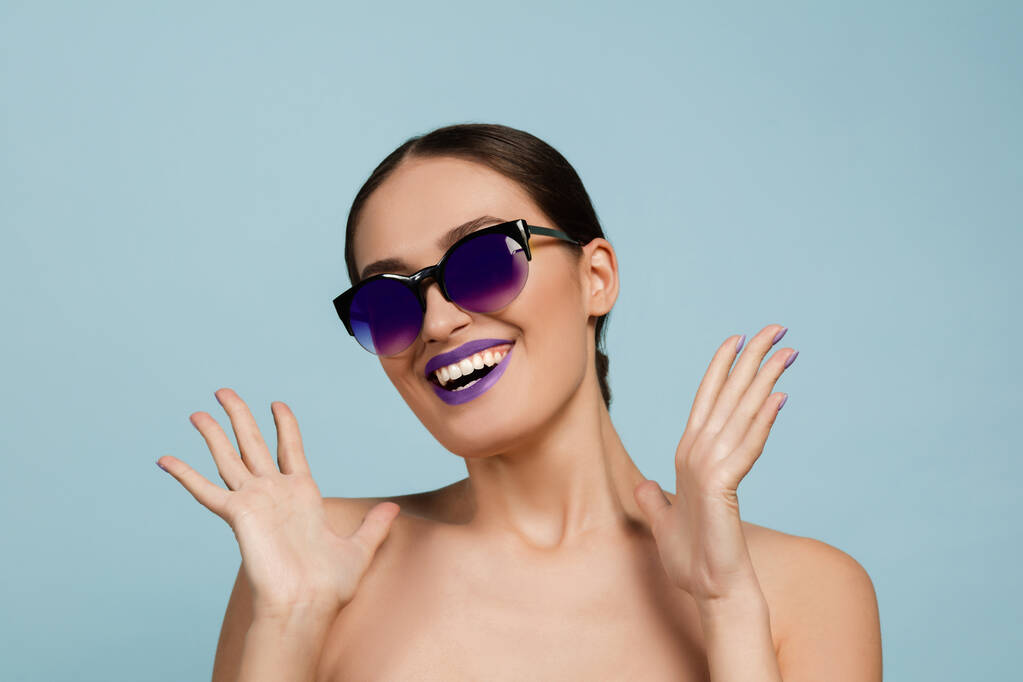 Porträt einer schönen jungen Frau mit hellem Make-up isoliert auf blauem Studiohintergrund - Foto, Bild