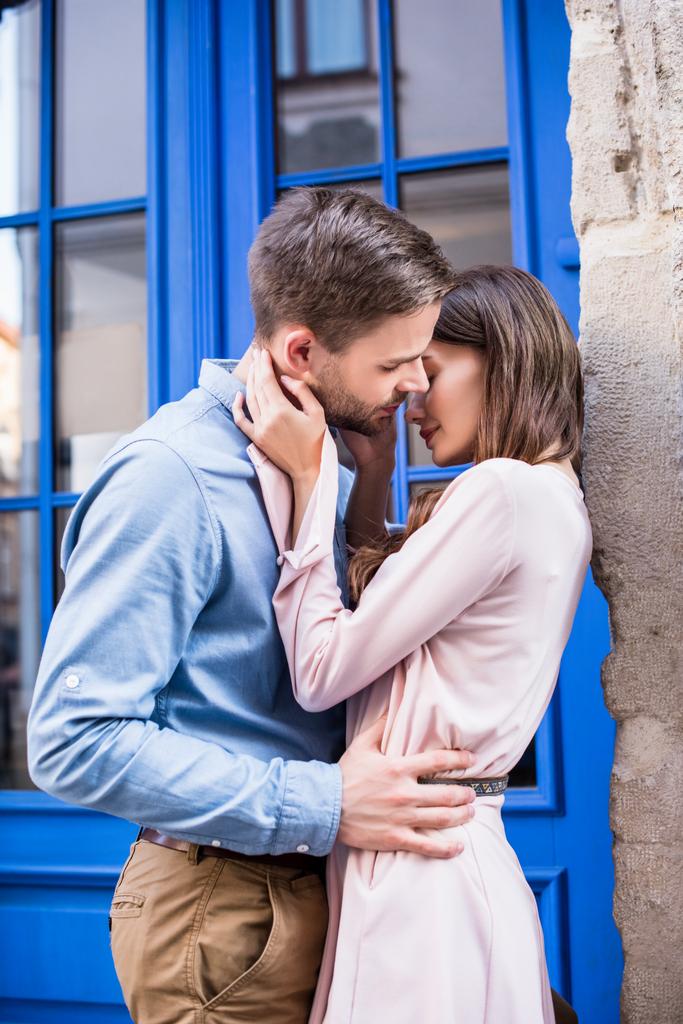jovem casal beijando na rua enquanto está perto da porta azul
 - Foto, Imagem
