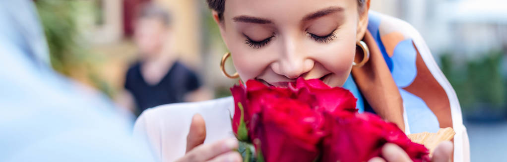 bijgesneden weergave van de mens presenteren boeket rozen aan gelukkig vriendin, panoramisch schot - Foto, afbeelding