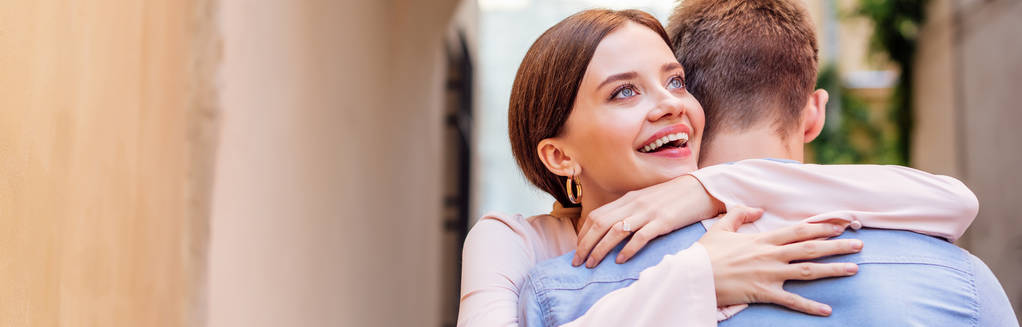 Panoramaaufnahme einer glücklichen jungen Frau, die ihren Freund umarmt  - Foto, Bild