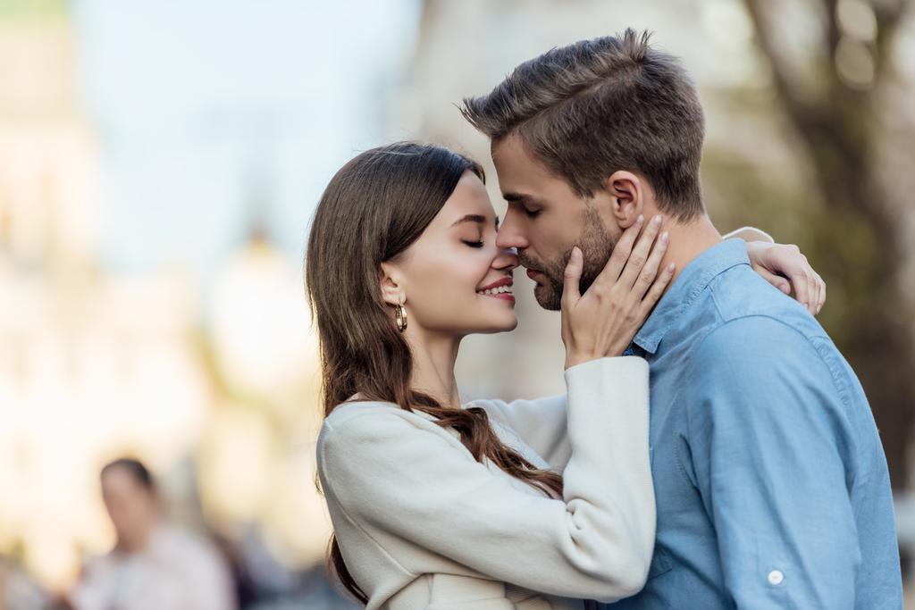 Kapalı gözlü mutlu kız sokakta yakışıklı erkek arkadaşını öpüyor. - Fotoğraf, Görsel