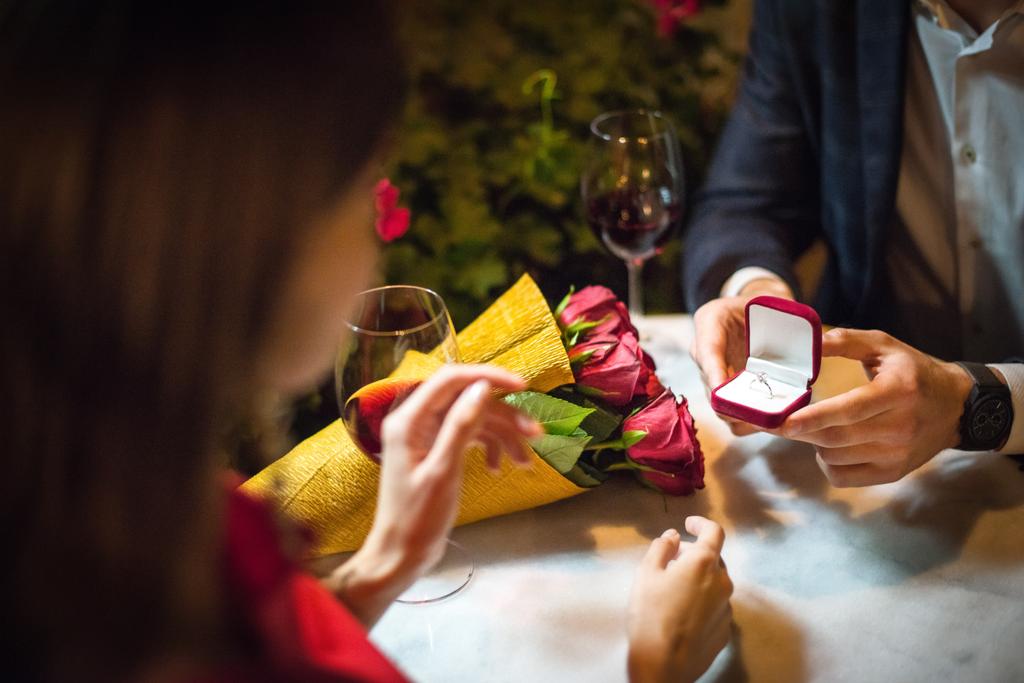 Teilansicht eines Mannes, der Freundin Ehering überreicht, während er einen Heiratsantrag macht - Foto, Bild