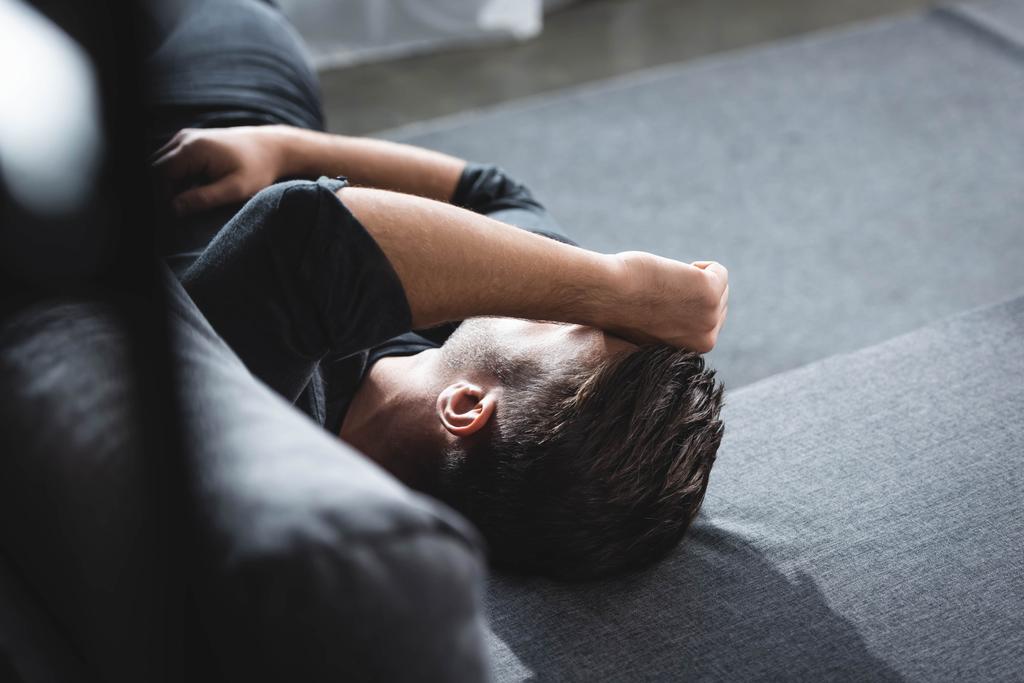 magas szög kilátás férfi fejfájás fekvő kanapén az apartmanban  - Fotó, kép