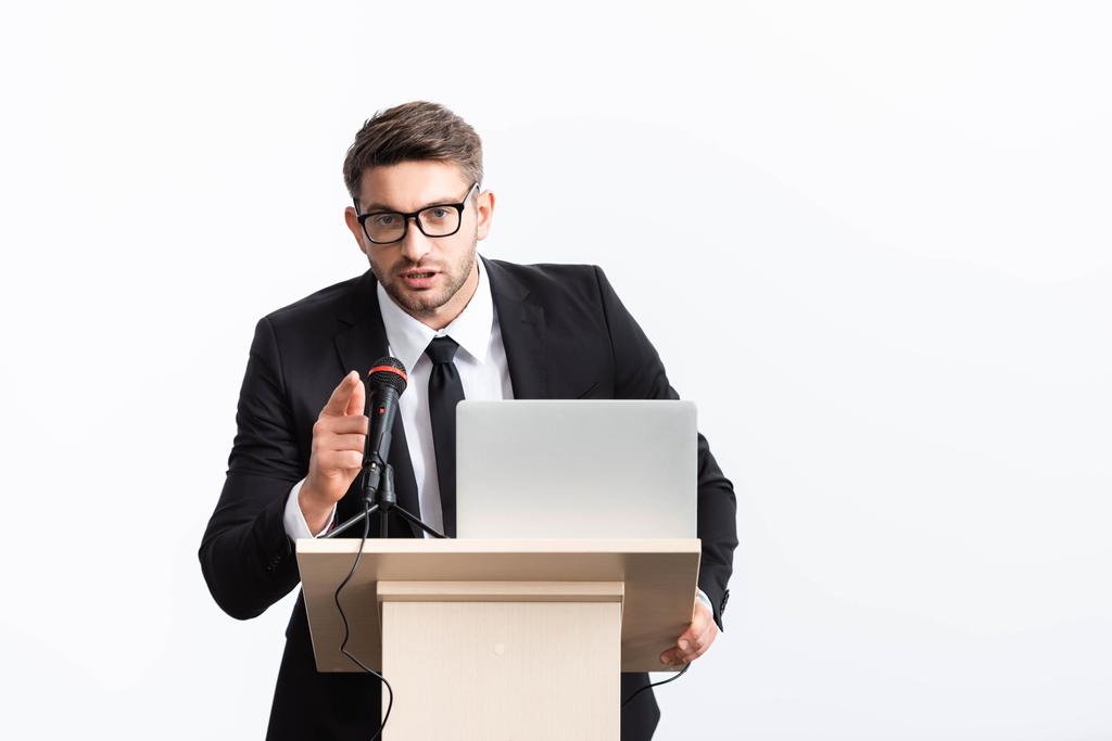 表彰台に立つスーツ姿のビジネスマンが白で隔絶された会議で指を指差す - 写真・画像