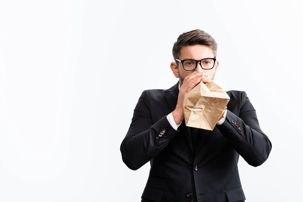 scared businessman in suit breathing in paper bag during conference isolated on white  - 写真・画像