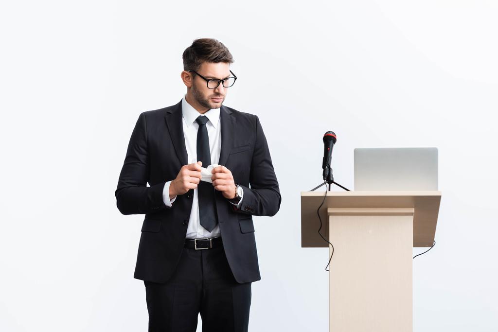 asustado hombre de negocios en traje de pie cerca de tribuna podio durante conferencia aislado en blanco
  - Foto, imagen