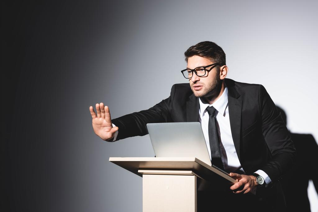 homme d'affaires effrayé en costume avec la main tendue debout au podium tribune pendant la conférence sur fond blanc
  - Photo, image