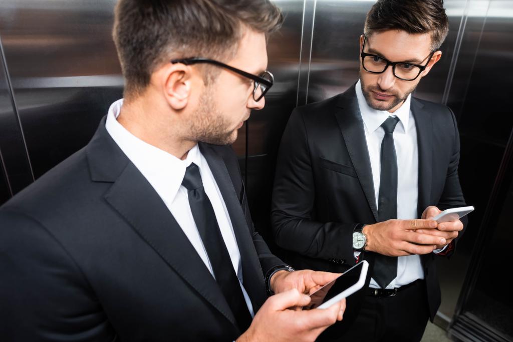 foyer sélectif de l'homme d'affaires en costume tenant smartphone et regardant miroir dans l'ascenseur
 - Photo, image