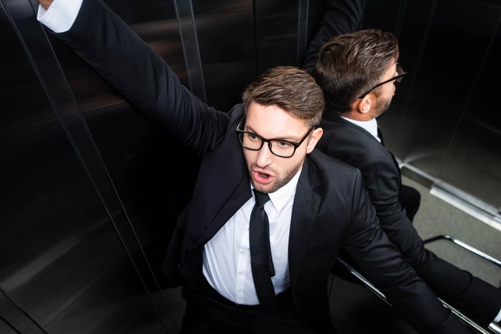 high angle view of scared businessman in suit with claustrophobia in elevator - Photo, Image