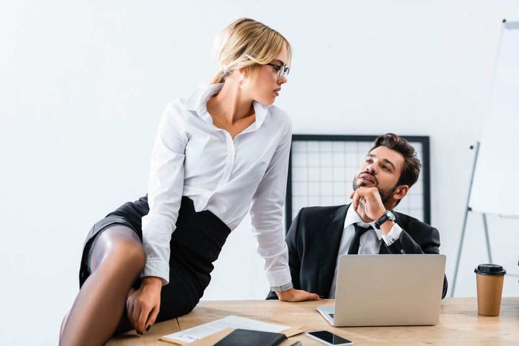 Сексуальна секретарка сидить на столі під час флірту з бізнесменом
 - Фото, зображення
