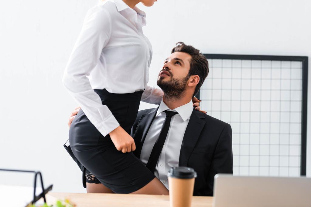 Przycięty widok bizneswoman dotykając sexy biznesmen w miejscu pracy - Zdjęcie, obraz