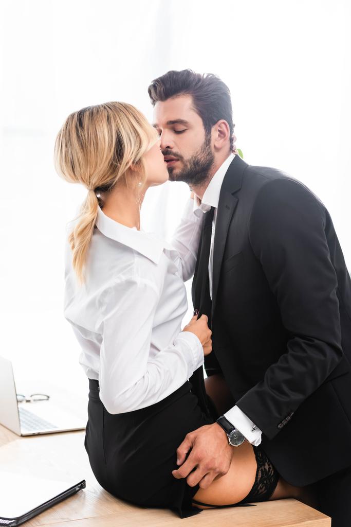 Geschäftsmann zieht Rock aus, während er sexy Frau auf Bürotisch küsst - Foto, Bild