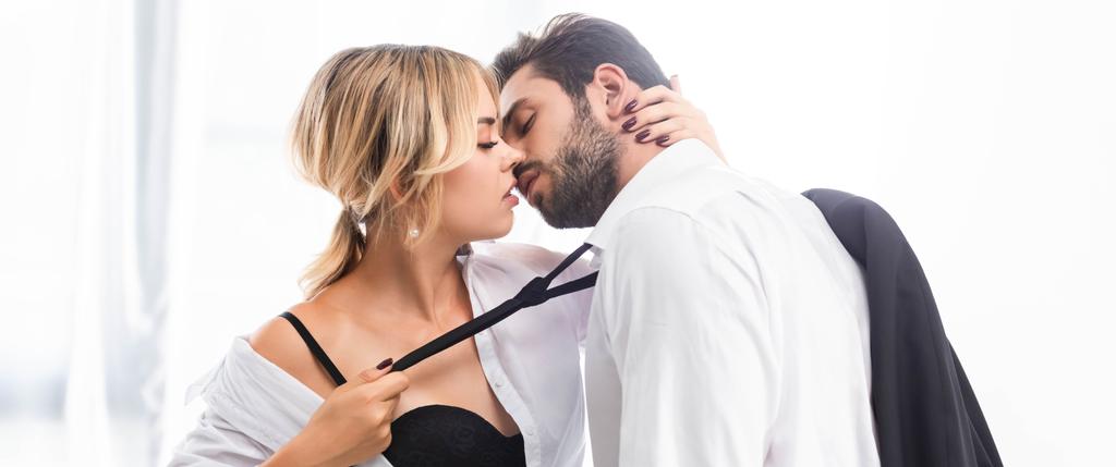 Sexy žena tahání businessman kravatu při flirtování v kanceláři, panoramatický výstřel - Fotografie, Obrázek
