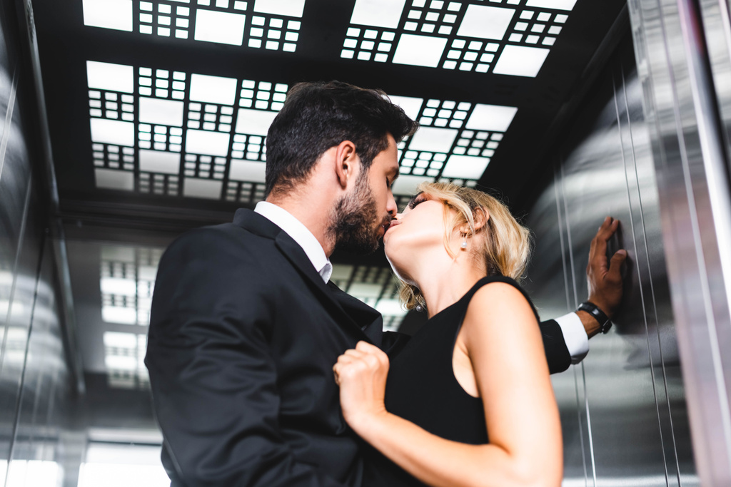 Biznesmen całuje kolegę w biurowej windzie - Zdjęcie, obraz