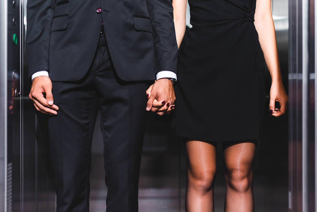 Ořezaný pohled na obchodní pár držící se za ruce v kancelářském výtahu  - Fotografie, Obrázek