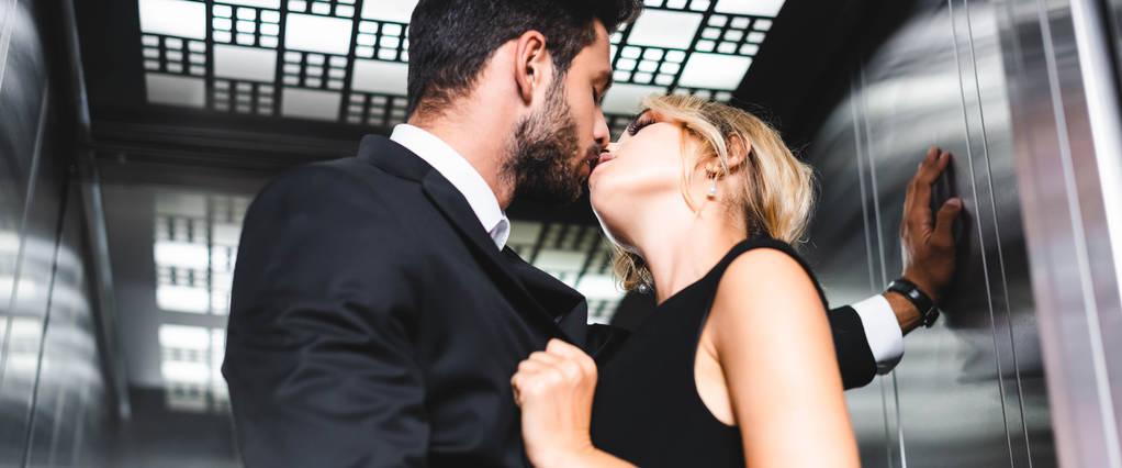 Panorâmica tiro de homem de negócios beijando mulher no elevador do escritório
 - Foto, Imagem