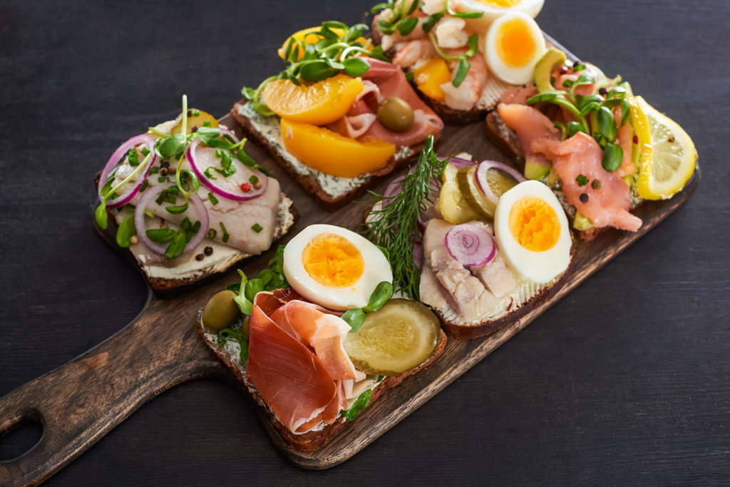 селективный фокус ржаного хлеба с датскими бутербродами смореброда на серой поверхности
  - Фото, изображение